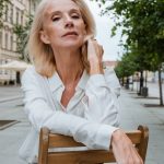 woman in white dress shirt sitting on brown wooden chair
